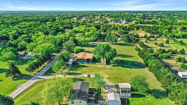 an aerial view of residential houses with outdoor space and trees