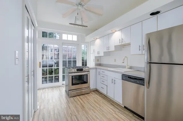 a kitchen with stainless steel appliances granite countertop a refrigerator a sink dishwasher a stove and white countertops with wooden floor