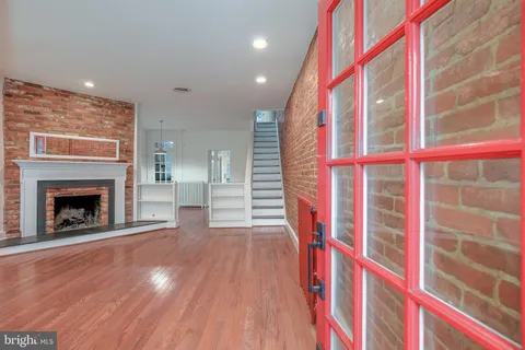 a view of an empty room with wooden floor and a fireplace