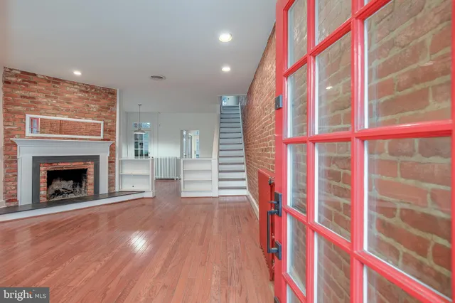 a view of an empty room with wooden floor and a fireplace