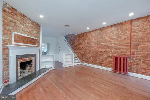 an empty room with wooden floor fireplace and windows
