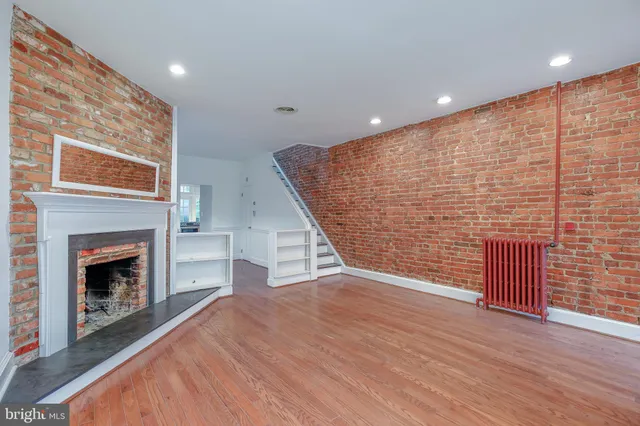 an empty room with wooden floor fireplace and windows