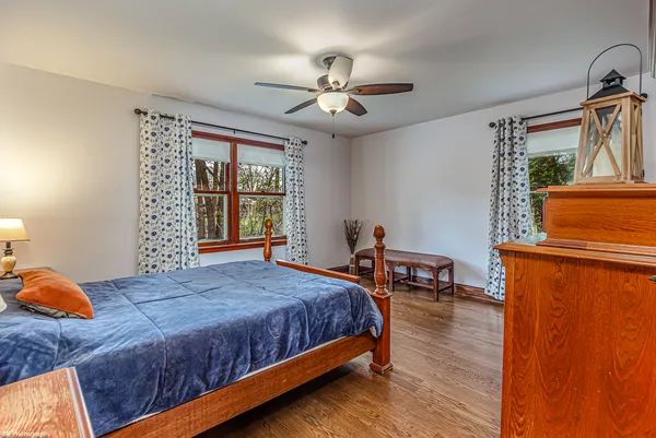 a bedroom with a bed a dresser and wooden floor