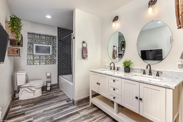 a spacious bathroom with double vanity a mirror and a lamp