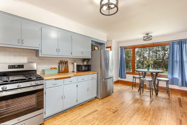 a kitchen with granite countertop a stove a sink dishwasher and white cabinets with wooden floor