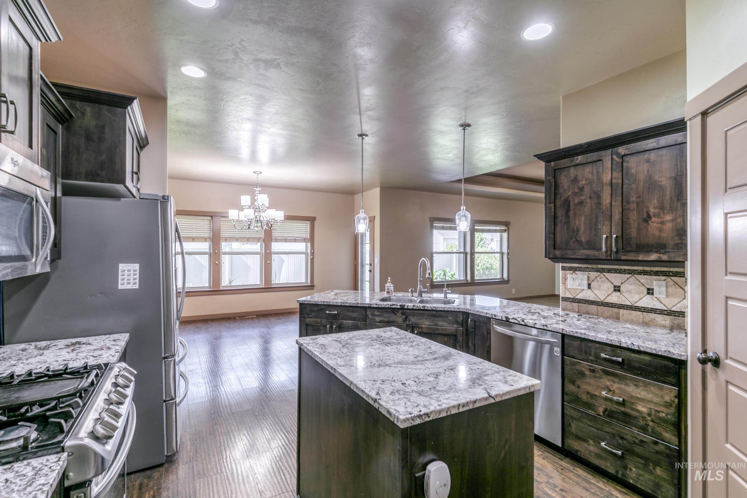 4316 Middlesboro Way Caldwell, ID 83607 - Photo 8 of 33 Kitchen featuring a spacious island with a double basin sink and stone countertop, wood-finish flooring, recessed lighting, and stainless steel appliances