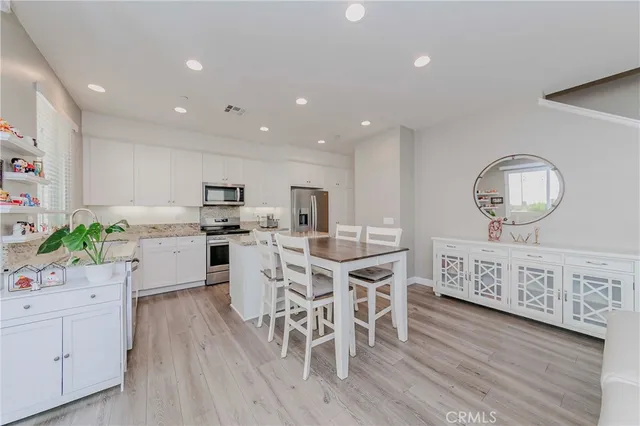 a kitchen with stainless steel appliances granite countertop a white cabinets stove and a wooden floor