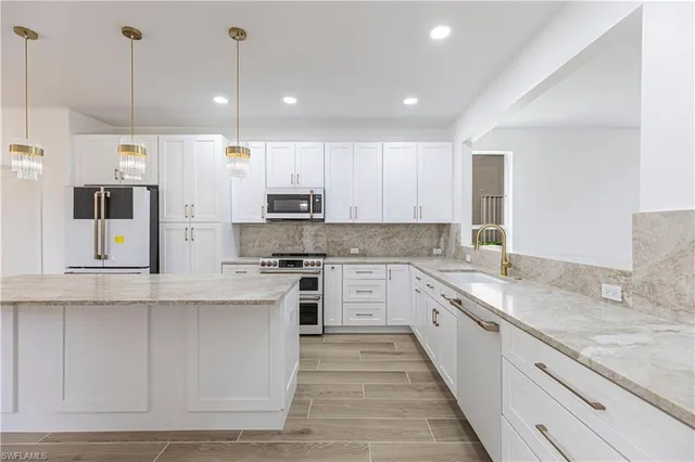 a large kitchen with stainless steel appliances granite countertop a stove a sink and a refrigerator