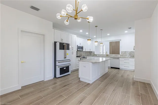 a large kitchen with a center island stainless steel appliances and cabinets