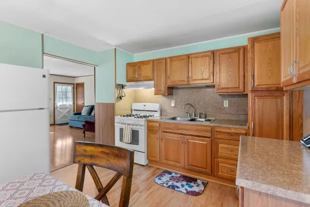 a kitchen with stainless steel appliances granite countertop a stove a sink dishwasher and a refrigerator with wooden cabinets