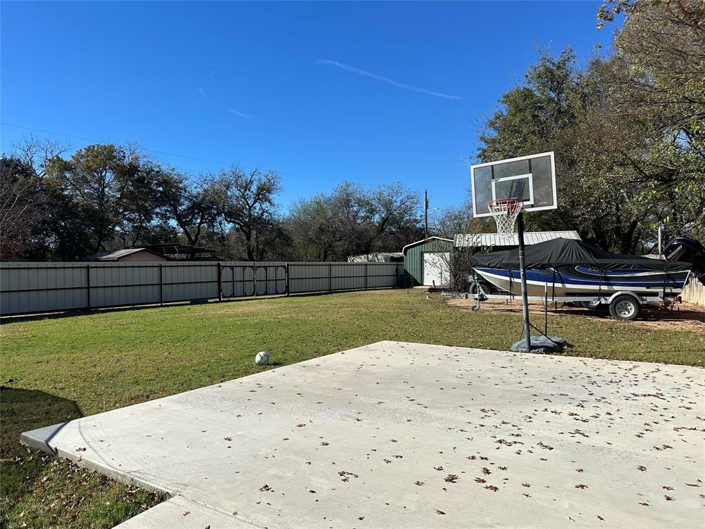 101 Twin Creek Road Comanche, TX 76442 - Photo 10 of 28 Fenced backyard featuring a storage shed, basketball hoop, and a patio area