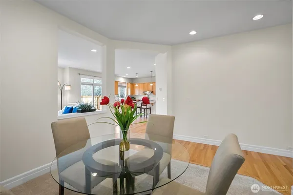 a kitchen with stainless steel appliances granite countertop a refrigerator a sink dishwasher a stove a dining table and chairs with wooden floor