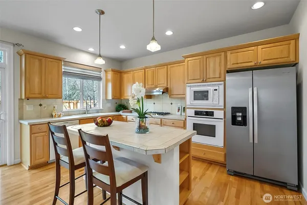 a kitchen with stainless steel appliances a dining table and chairs in it