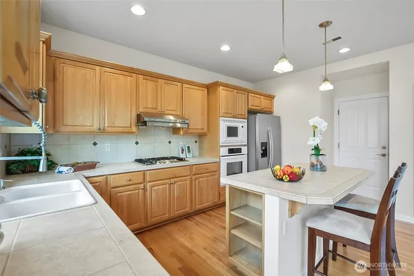 an open kitchen with sink and white cabinets with wooden floor