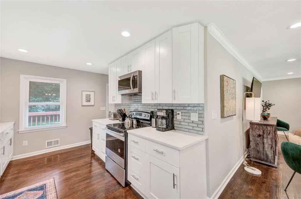 1376 Sandtown Road Southwest Marietta, GA 30008 - Photo 12 of 25 a kitchen with stainless steel appliances a white stove top oven a sink a refrigerator and white cabinets with wooden floor