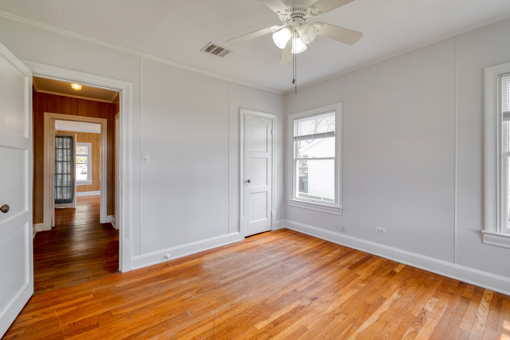 710 North Ave H Elgin, TX 78621 - Photo 15 of 25 Bedroom view toward hallway. Wood floors, a ceiling fan, and multiple windows