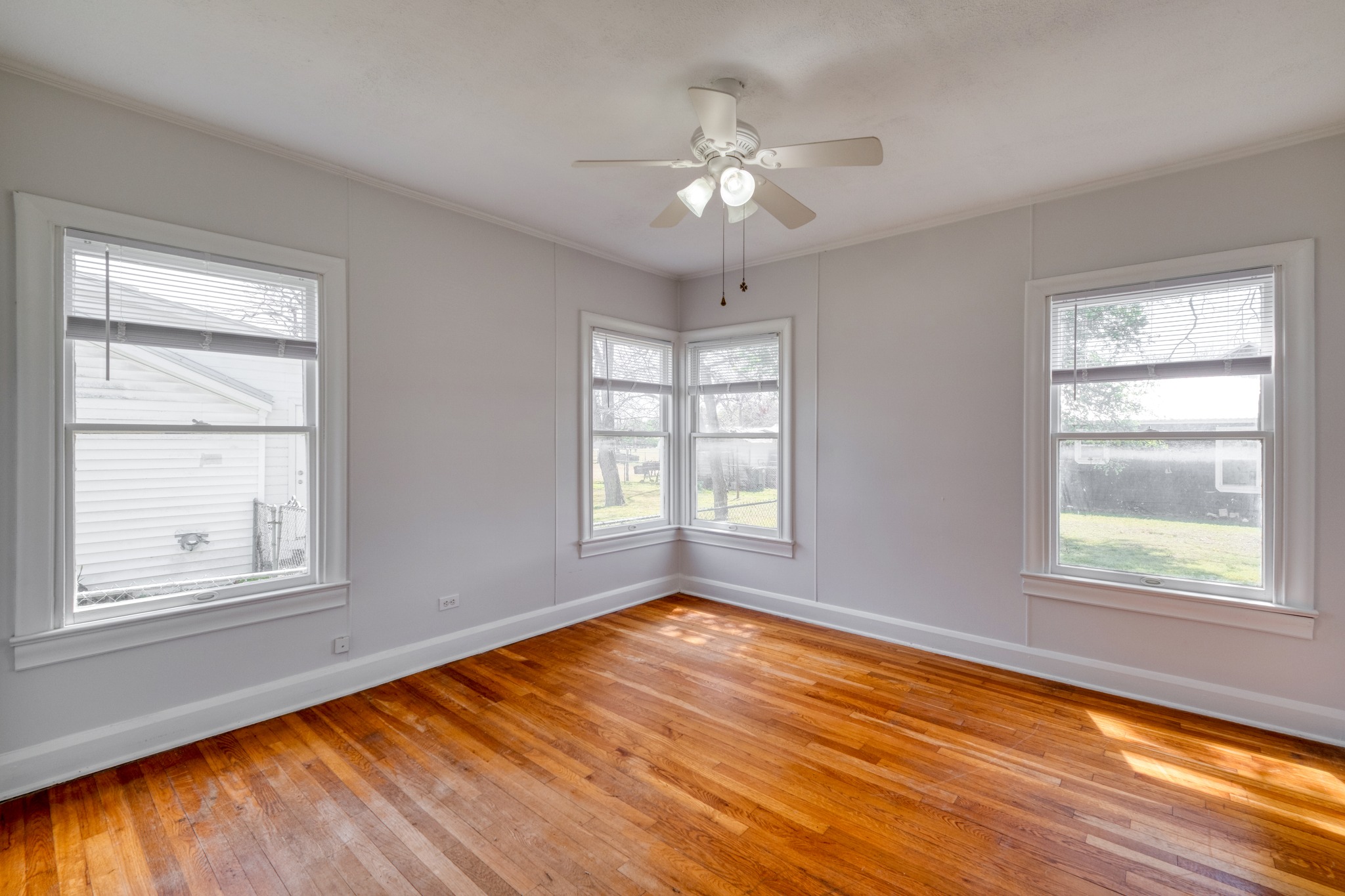 710 North Ave H Elgin, TX 78621 - Photo 16 of 25 Bedroom view from hallway door. Wood floors, a ceiling fan, and multiple windows