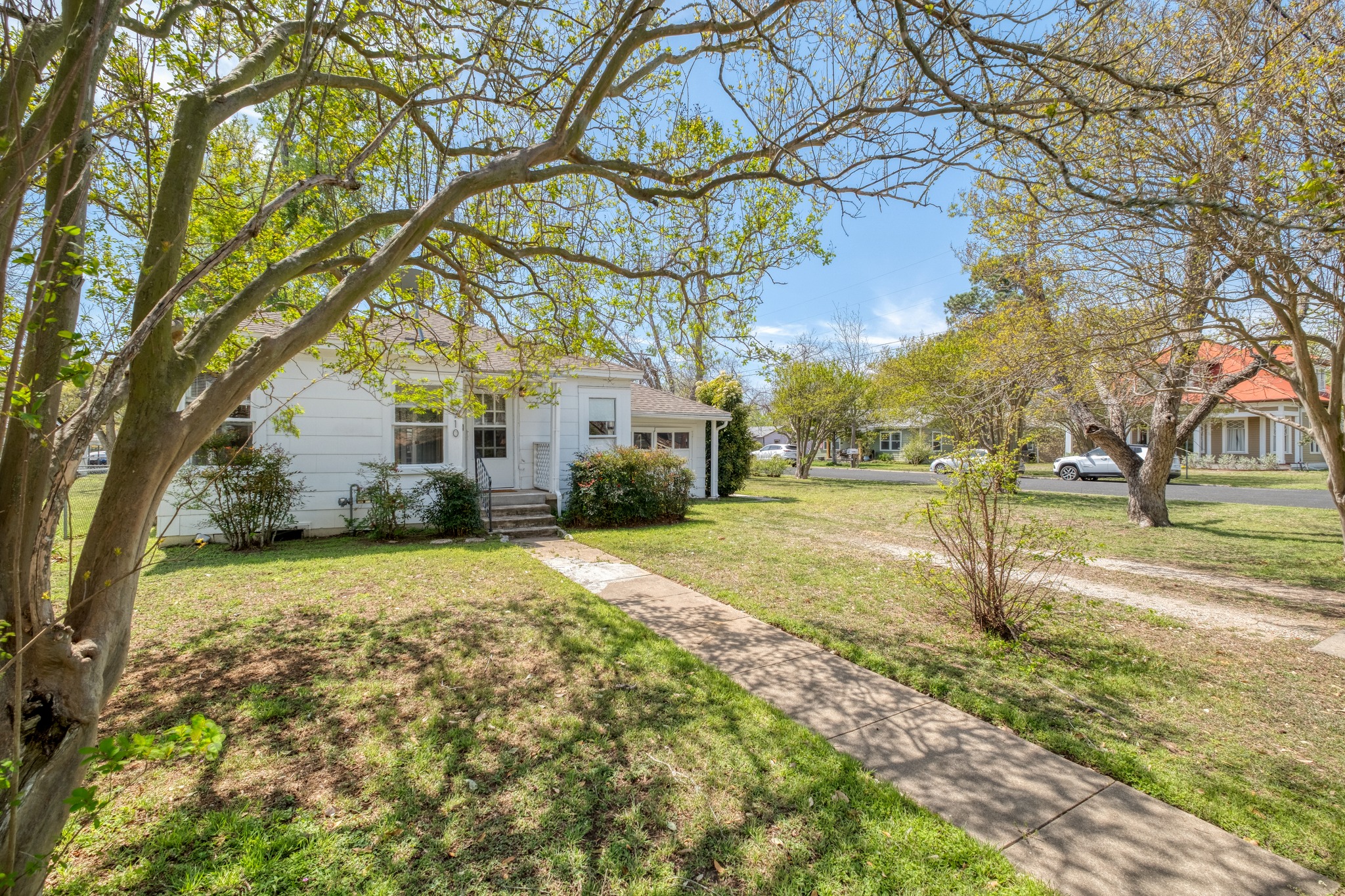 710 North Ave H Elgin, TX 78621 - Photo 22 of 25 View of front of home from northeast corner of the property featuring a single-car attached garage, with dirt driveway.
