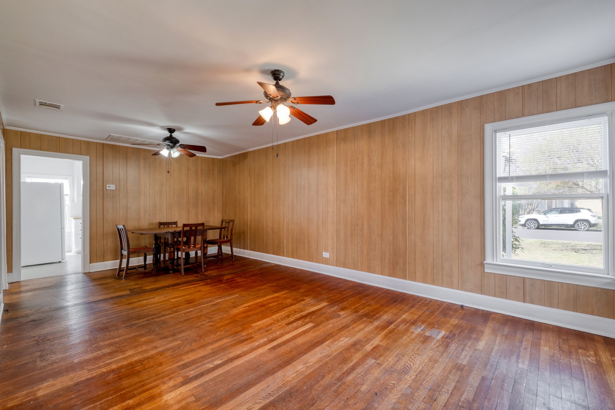 710 North Ave H Elgin, TX 78621 - Photo 3 of 25 Living and dining room; view from front door toward kitchen. Wood flooring, paneled walls and ceiling fans.