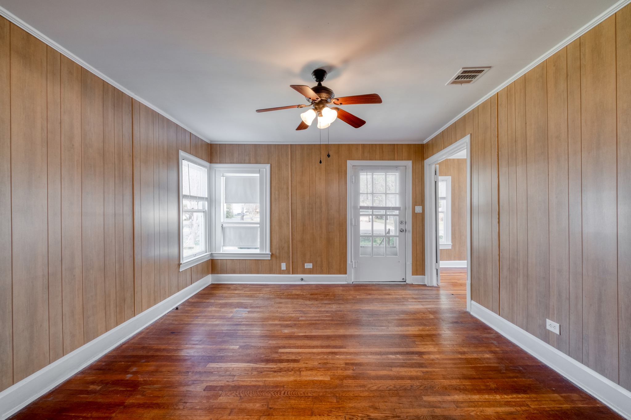 710 North Ave H Elgin, TX 78621 - Photo 4 of 25 Living and dining room, view toward front entry door. Wood floors, paneled walls and ceiling fan.