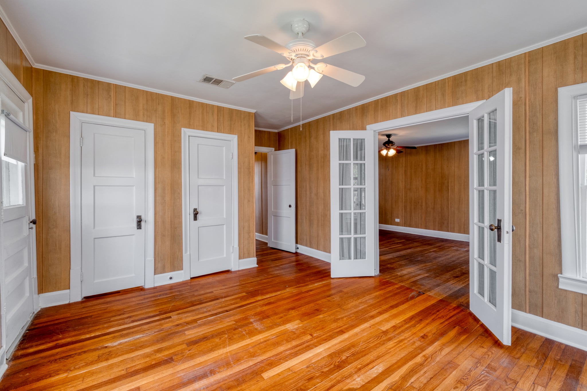 710 North Ave H Elgin, TX 78621 - Photo 5 of 25 Front Bedroom with french doors to living room. Wood flooring, paneled walls, white trim and ceiling fan.