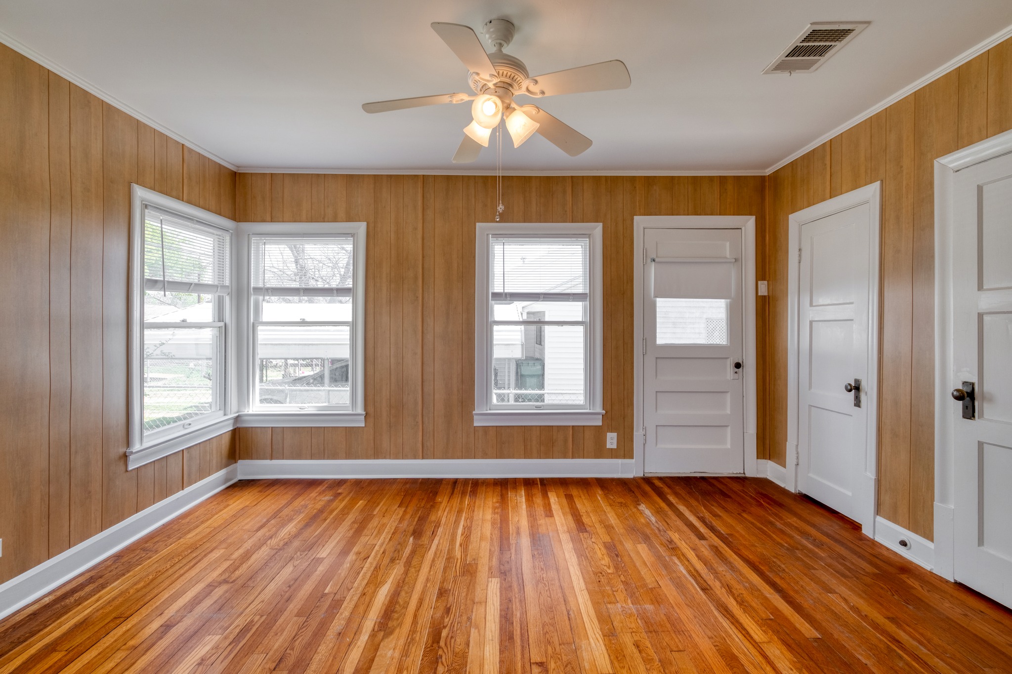 710 North Ave H Elgin, TX 78621 - Photo 7 of 25 Front bedroom, view from french doors connecting to the living room. Wood floors, wall paneling and ceiling fan.