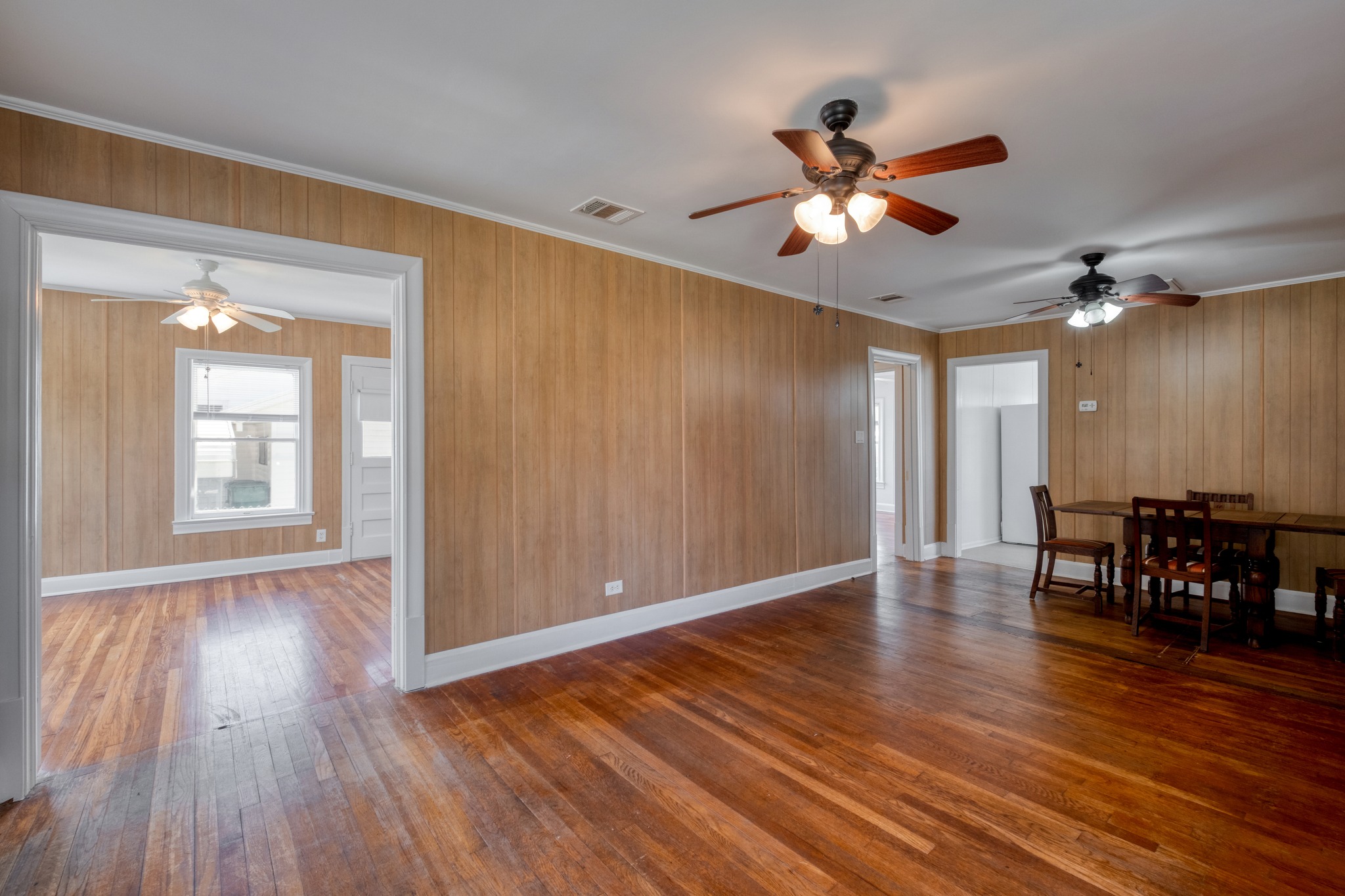 710 North Ave H Elgin, TX 78621 - Photo 8 of 25 Living room and dining room looking toward front bedroom. Wood floors, wall paneling, and ceiling fans.