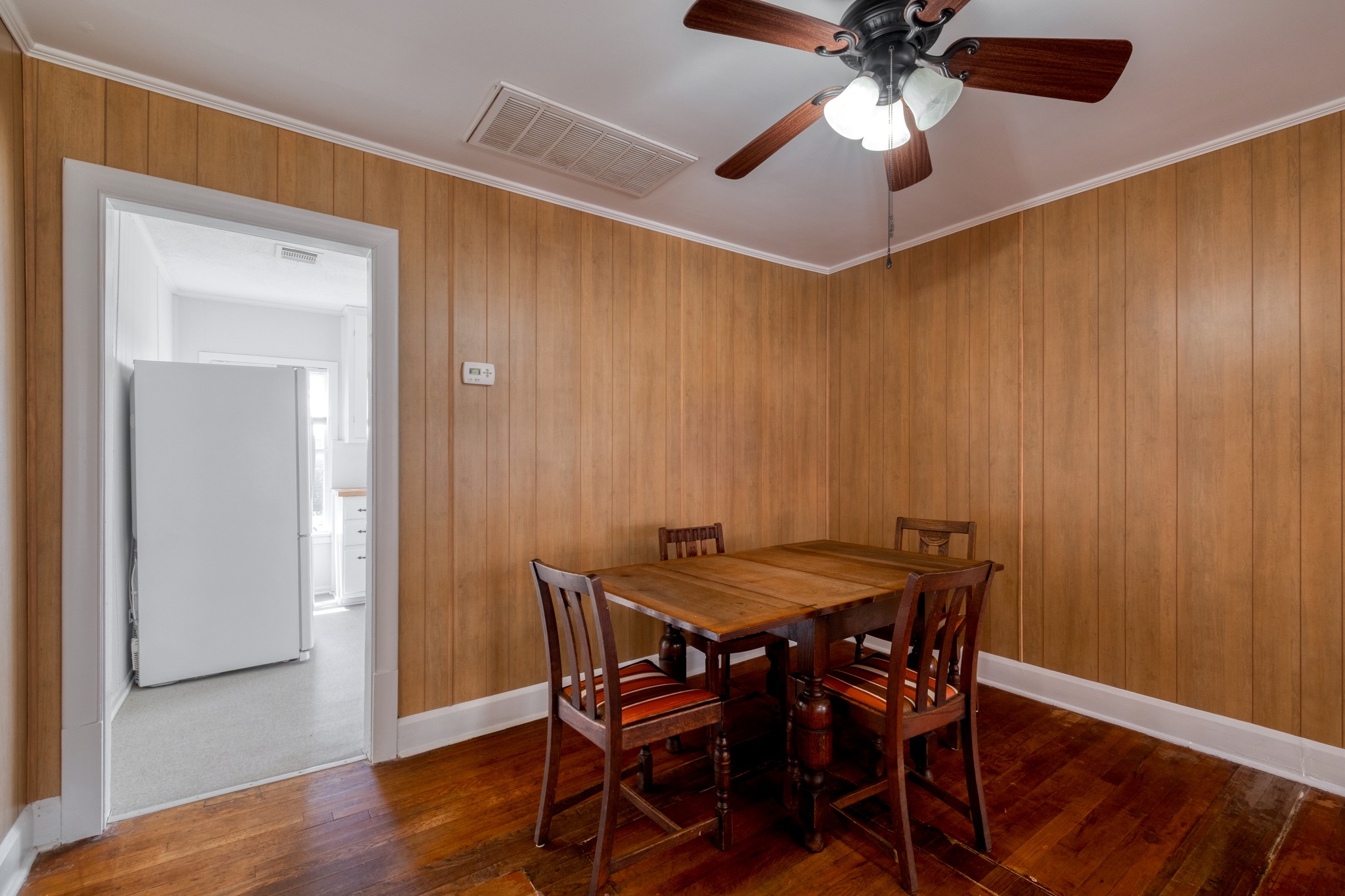 710 North Ave H Elgin, TX 78621 - Photo 9 of 25 Dining area with doorway into kitchen. Wood floors, wall paneling, and ceiling fan.