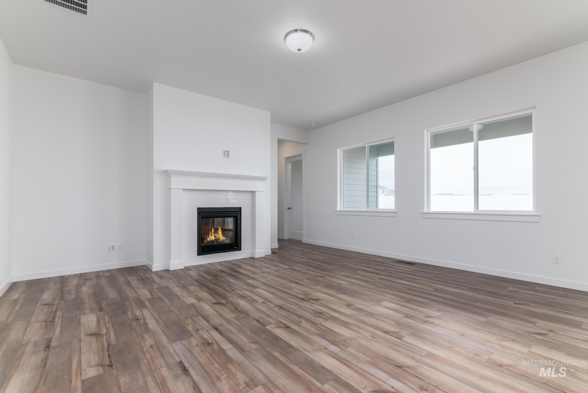 15232 Steel Cloud Avenue Caldwell, ID 83607 - Photo 4 of 33 Unfurnished living room featuring dark wood finished floors and a fireplace