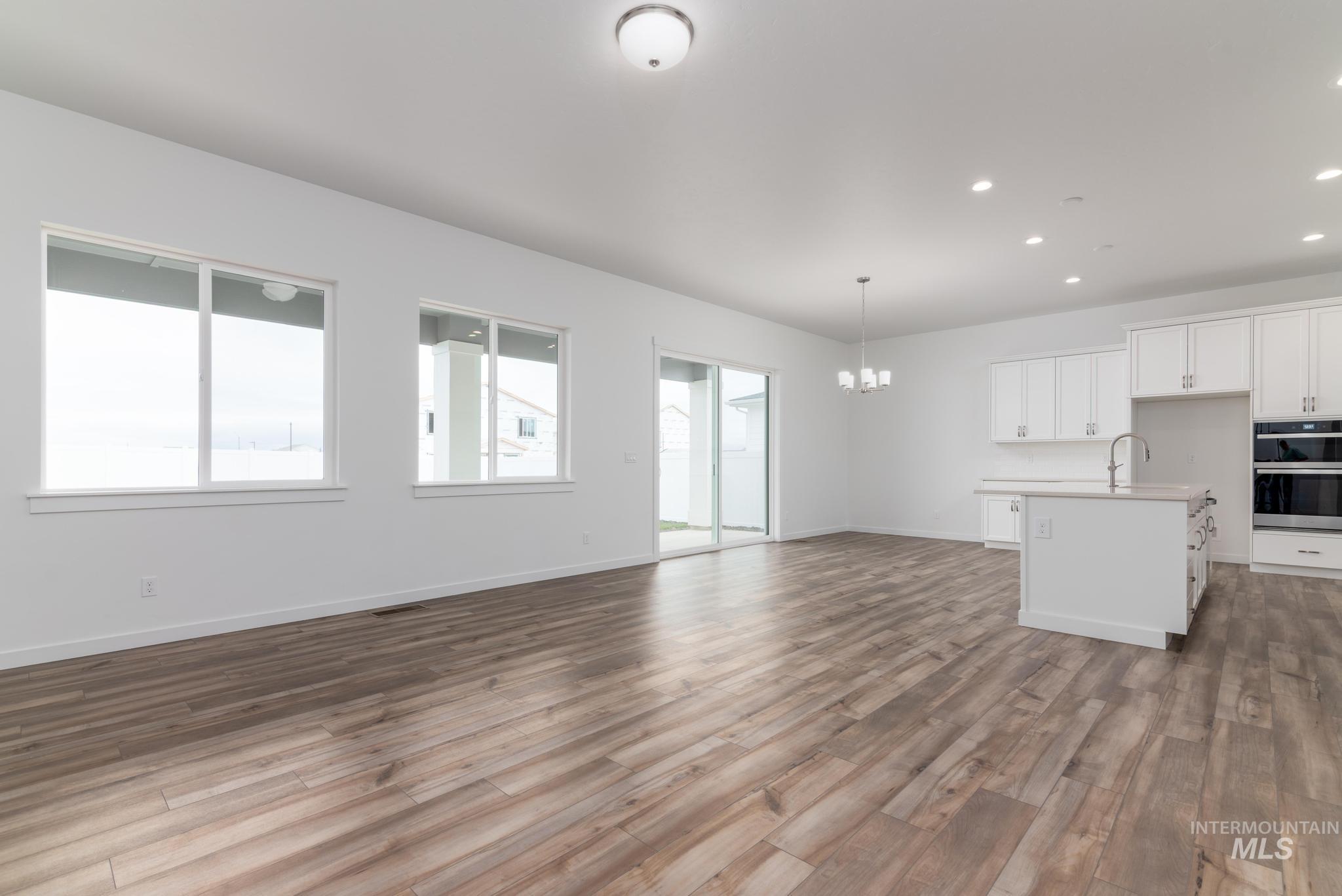 15232 Steel Cloud Avenue Caldwell, ID 83607 - Photo 32 of 33 Kitchen featuring white cabinets, open floor plan, light countertops, suspended lighting, and a center island with sink
