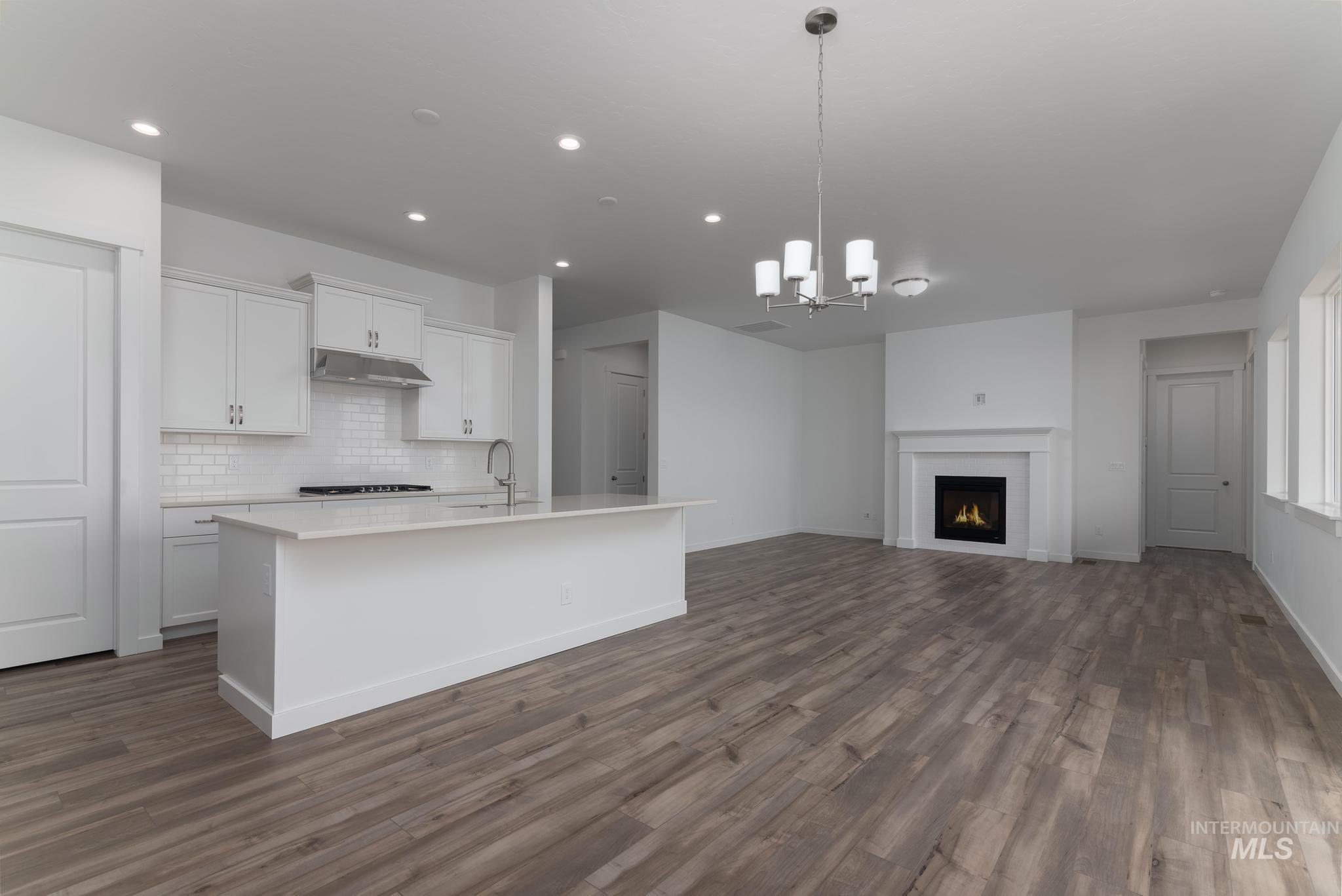 15232 Steel Cloud Avenue Caldwell, ID 83607 - Photo 33 of 33 Kitchen with white cabinets, suspended lighting, open floor plan, a center island with sink, and tasteful backsplash