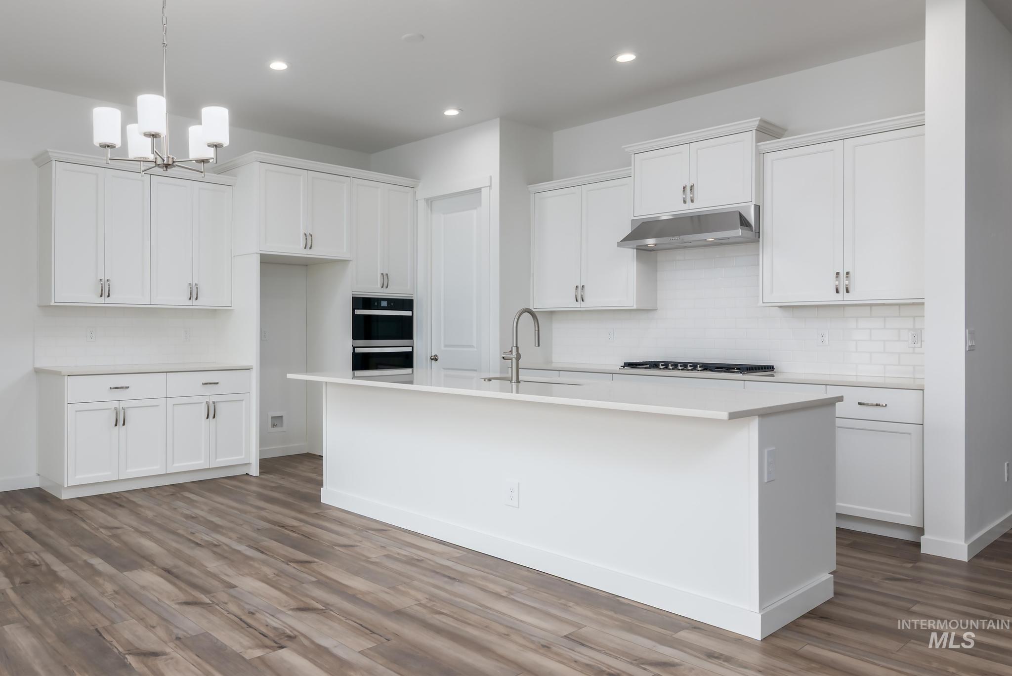 15232 Steel Cloud Avenue Caldwell, ID 83607 - Photo 7 of 33 Kitchen with white cabinets, a kitchen island with sink, a chandelier, dark wood-type flooring, and double wall oven