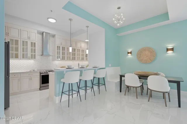 a kitchen with stainless steel appliances granite countertop a table chairs and a refrigerator