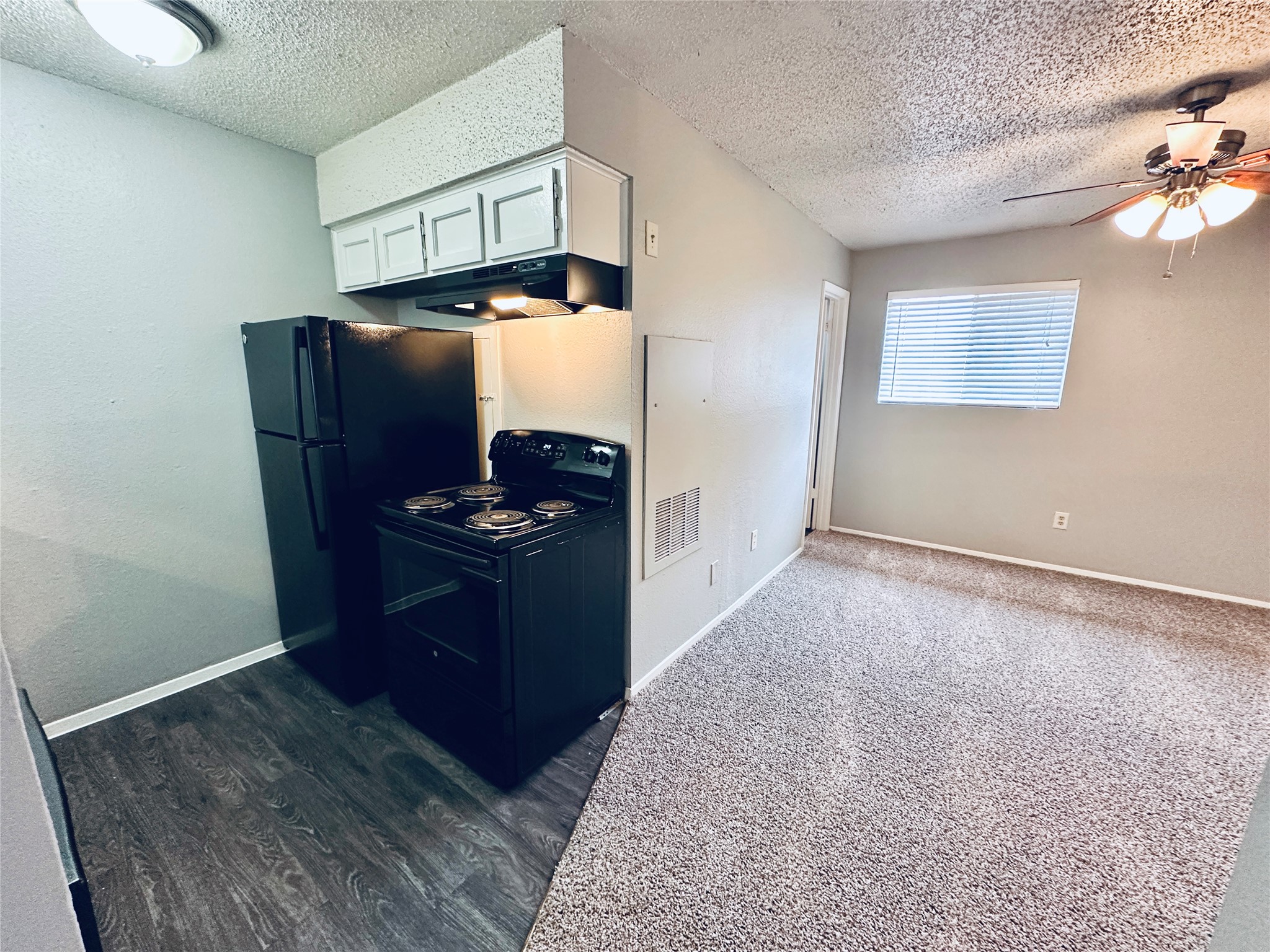 3702 South 2nd Street, Unit 203 Austin, TX 78704 - Photo 4 of 11 Kitchen with black appliances, a textured ceiling, white cabinetry, ceiling fan, and dark wood-style flooring