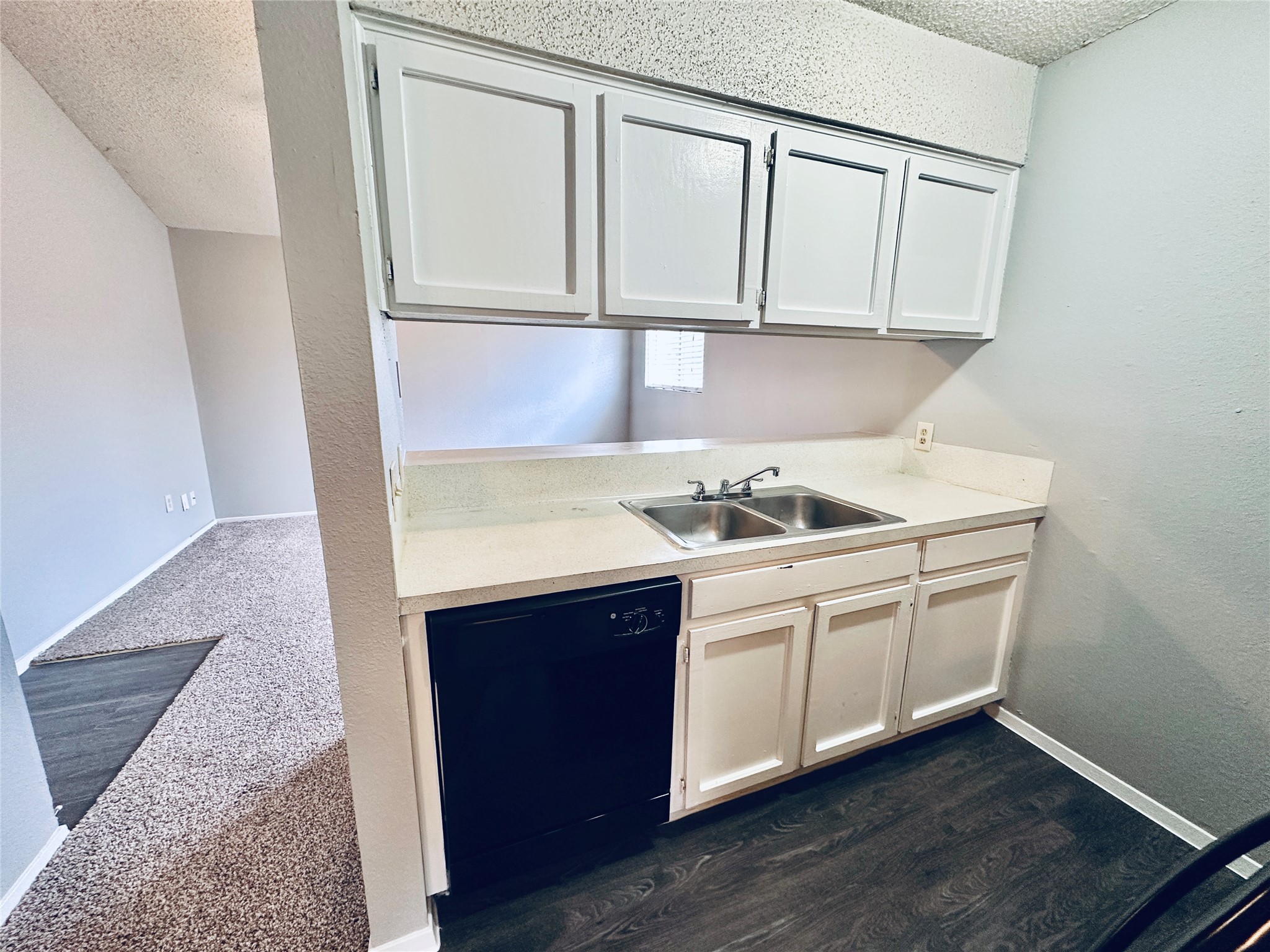 3702 South 2nd Street, Unit 203 Austin, TX 78704 - Photo 5 of 11 Kitchen featuring a textured ceiling, light countertops, dishwasher, dark wood-style flooring, and a textured wall