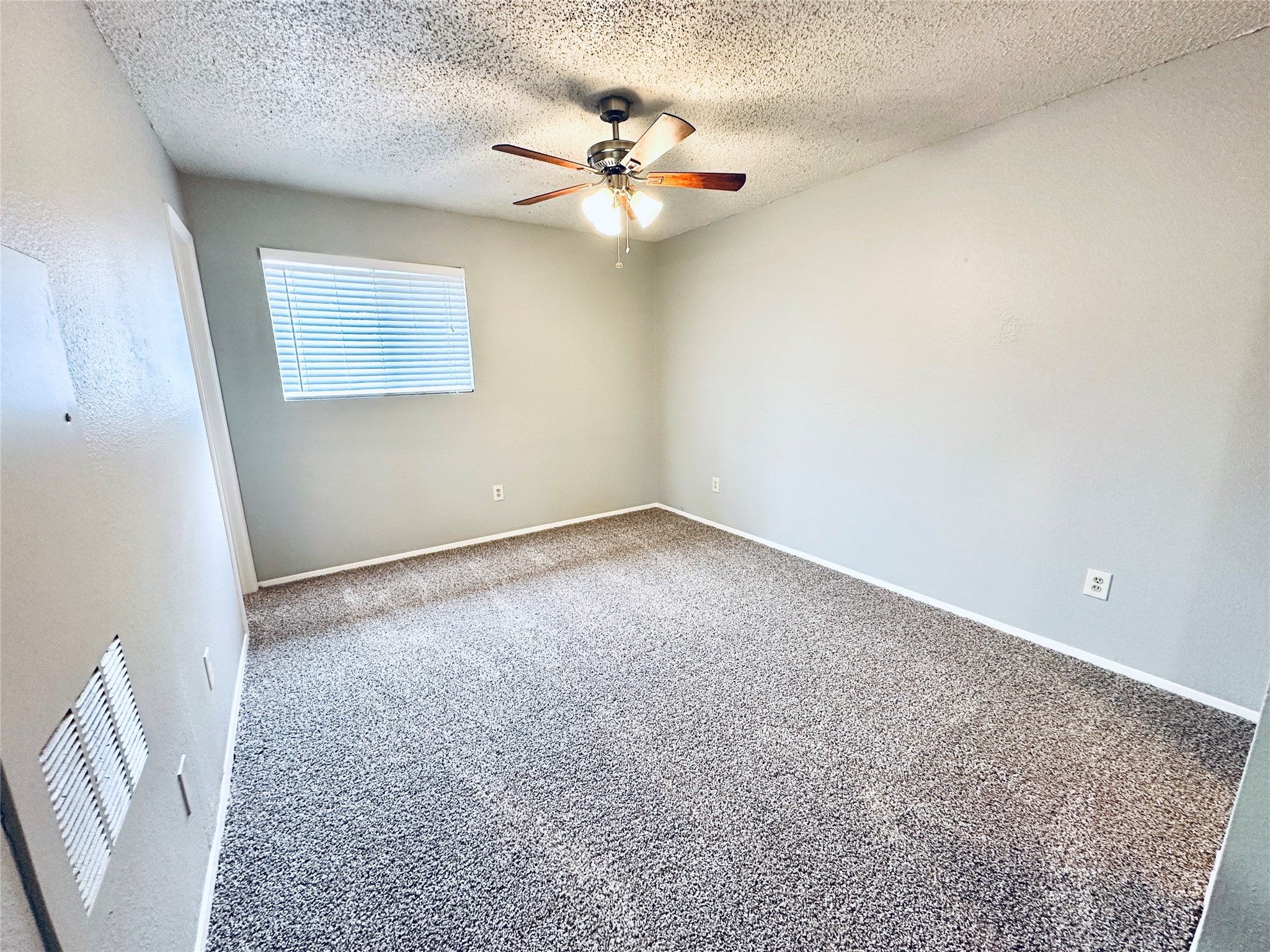 3702 South 2nd Street, Unit 203 Austin, TX 78704 - Photo 7 of 11 Unfurnished room featuring carpet flooring, a textured ceiling, and a ceiling fan