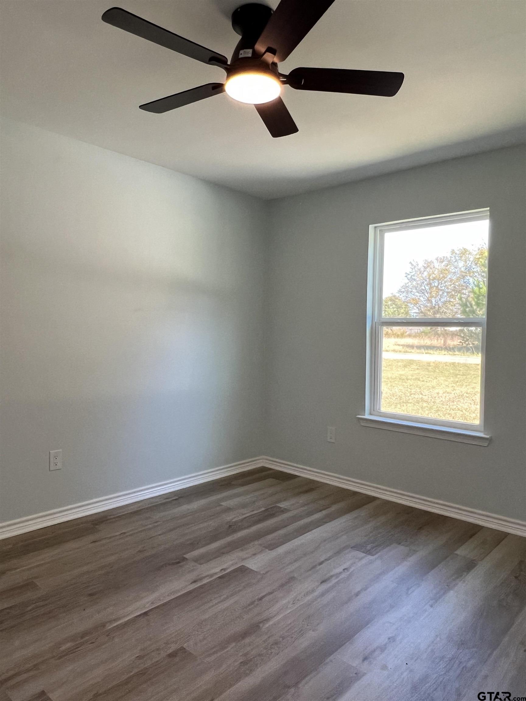 125 Pecan Drive Bullard, TX 75757 - Photo 14 of 16 an empty room with wooden floor ceiling fan and windows