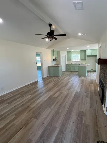 an empty room with wooden floor fireplace and fan