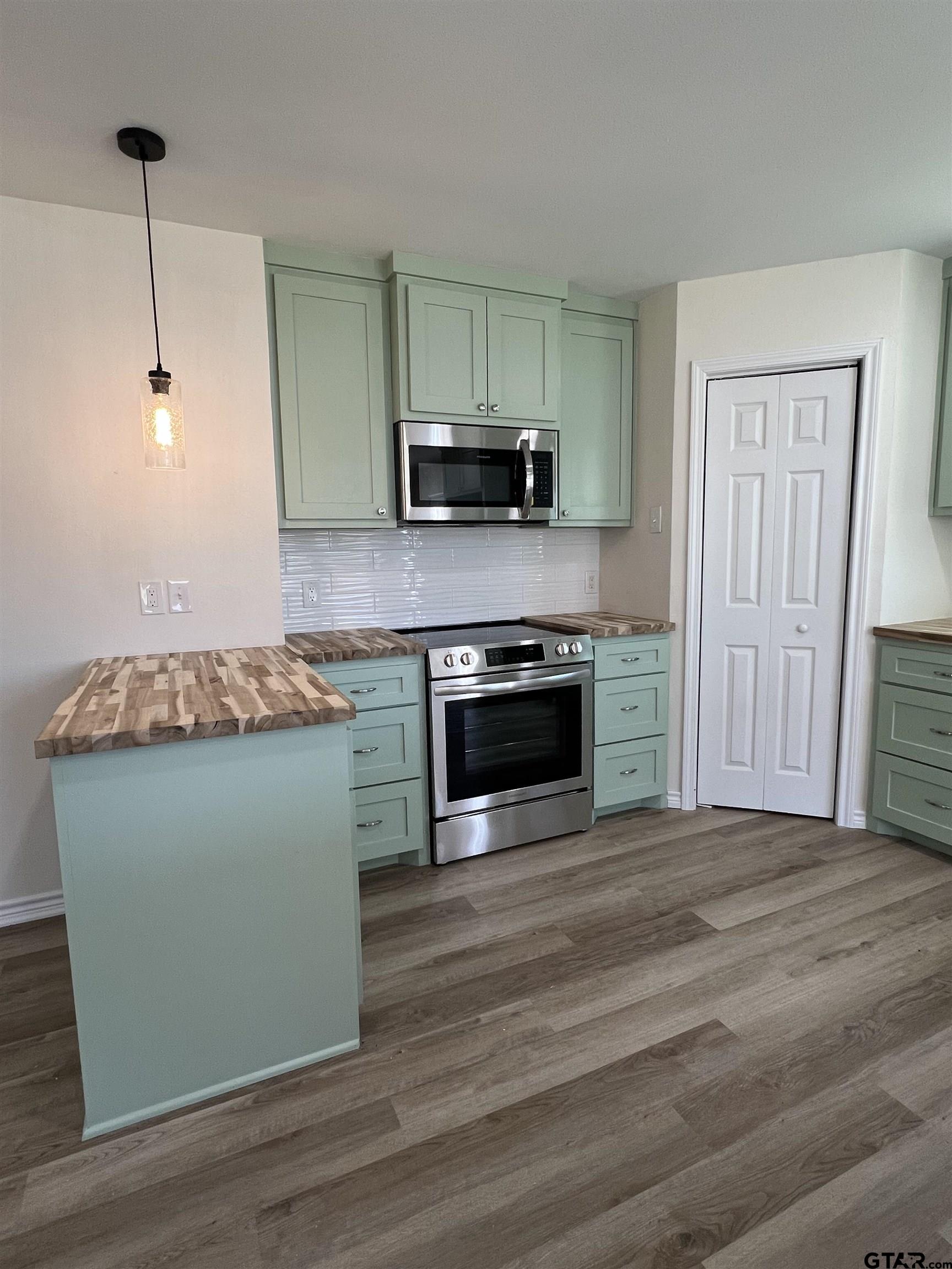 125 Pecan Drive Bullard, TX 75757 - Photo 5 of 16 a kitchen with granite countertop a stove and a wooden floors