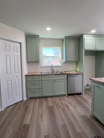 a kitchen with granite countertop a sink cabinets and wooden floors