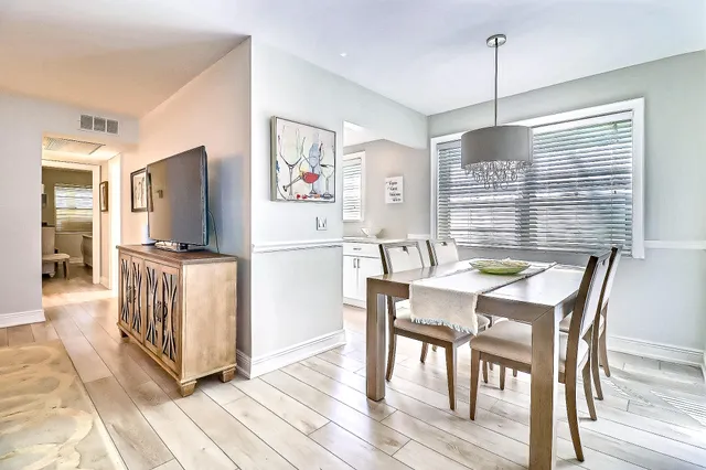 a kitchen with stainless steel appliances granite countertop white refrigerator a stove a dining table and chairs with wooden floor