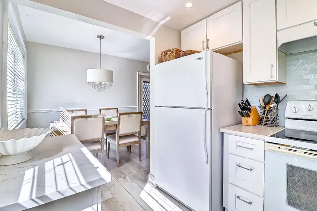 a kitchen with stainless steel appliances a refrigerator a sink a stove a dining table and chairs with wooden floor