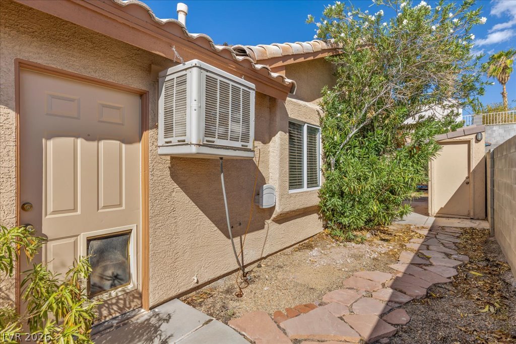120 Ringlore Road Henderson, NV 89015 - Photo 29 of 58 A stone pathway guides steps through the side yard past stucco walls under a tile roof.