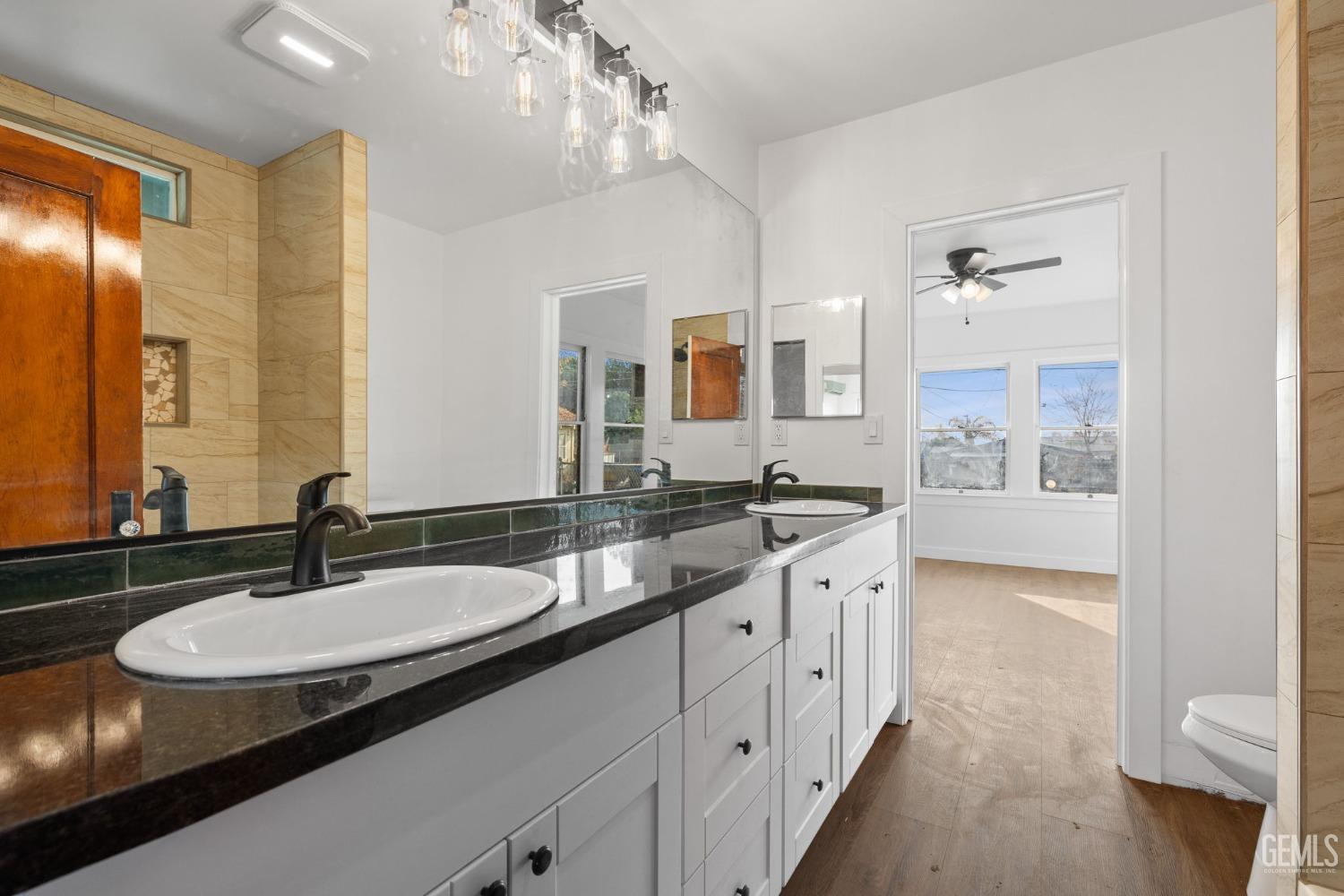 Undisclosed Address Bakersfield, CA 93308 - Photo 16 of 21 a bathroom with a granite countertop sink a large mirror and a shower
