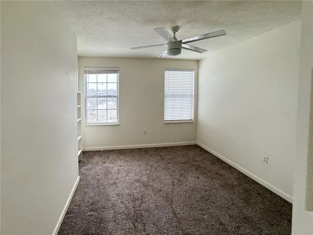 an empty room with windows and fan