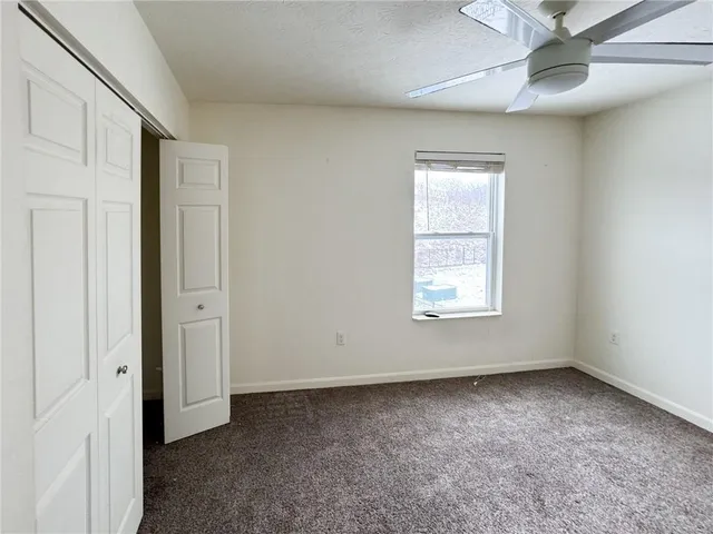 an empty room with a ceiling fan and windows
