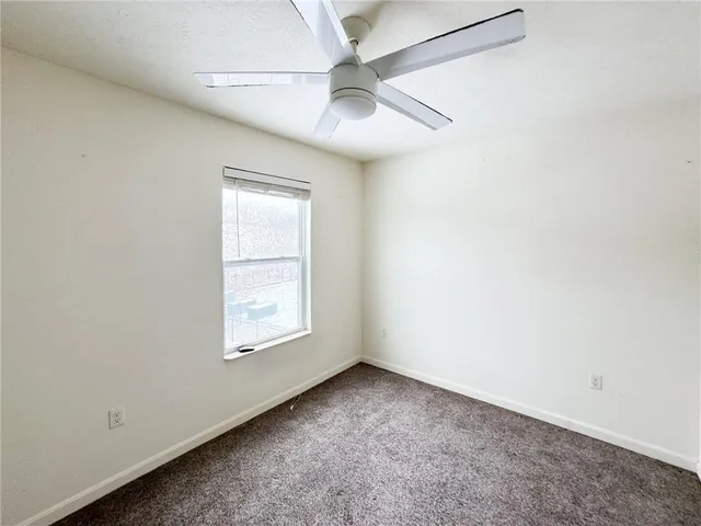 an empty room with a window and a ceiling fan