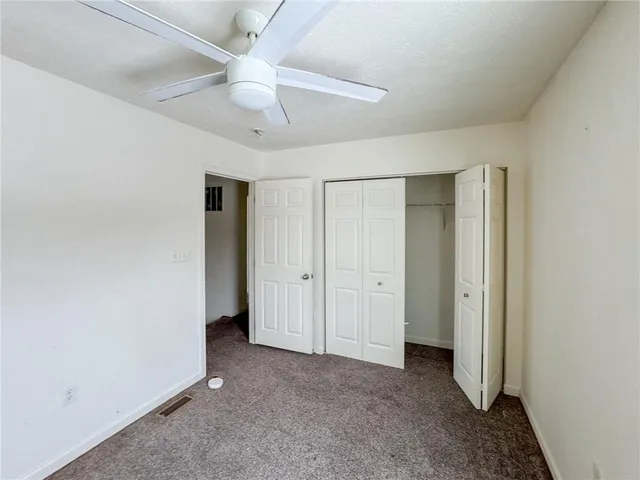 an empty room with a ceiling fan and carpet
