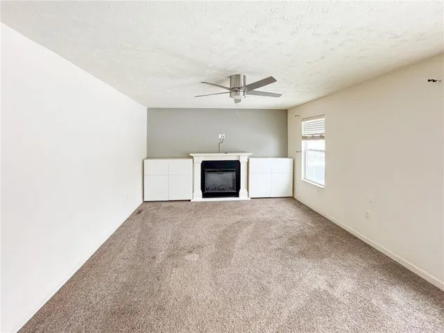an empty room with a fireplace and ceiling fan
