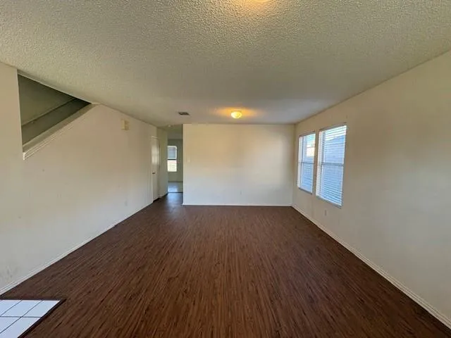 an empty room with wooden floor fireplace and windows